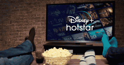 couple sitting on a couch watching Disney+ Hotstar on a television